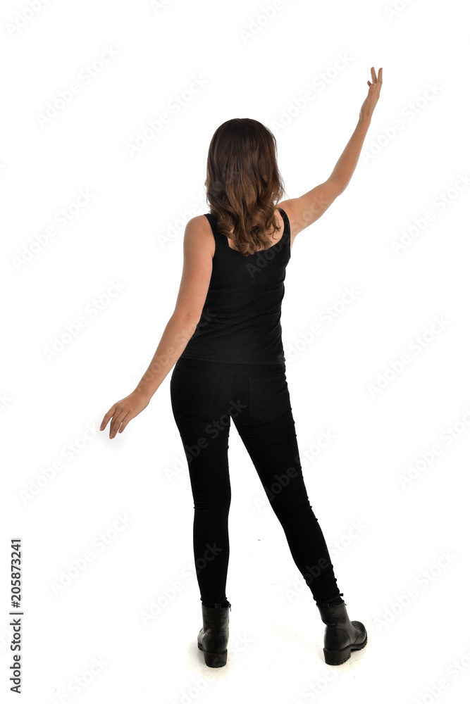 full length portrait of brunette girl wearing black singlet, jeans jeans and boots. standing pose, with back view. isolated on white studio background. full length portrait of brunette girl wearing black singlet, jeans jeans and boots. standing pose, with back view. isolated on white studio background.