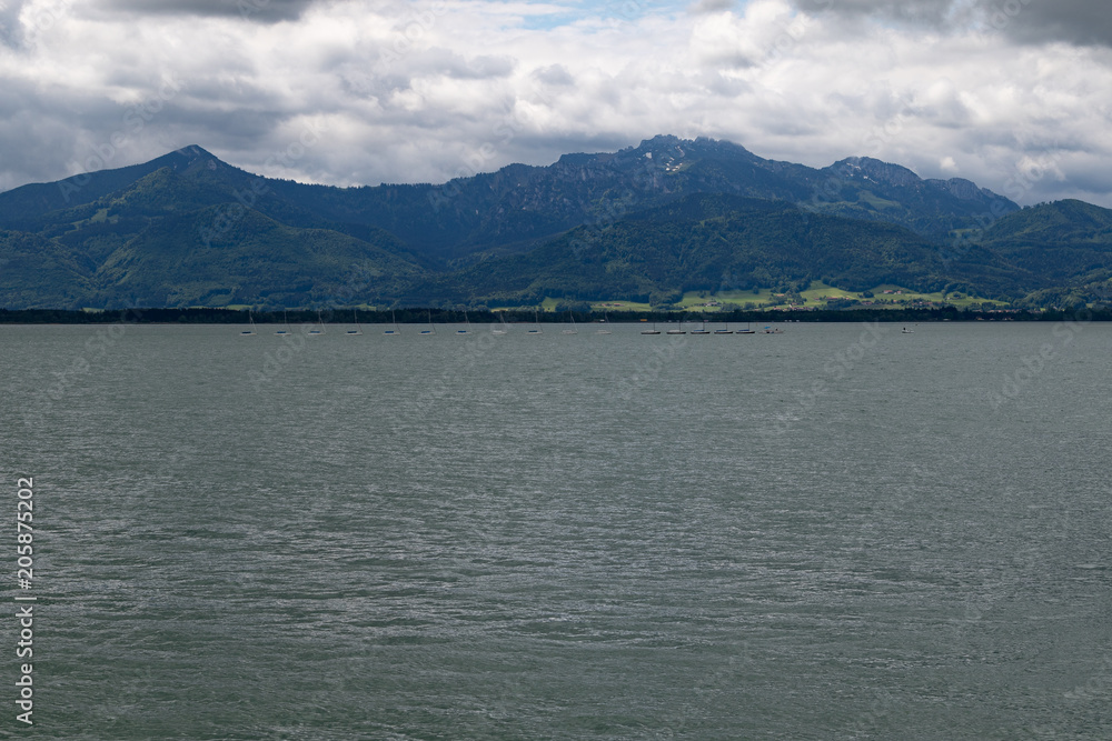 River side of a big lake in front of big mounts in bavaria under grey clouds 