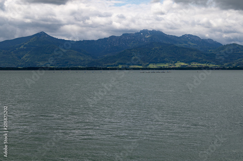 River side of a big lake in front of big mounts in bavaria under grey clouds 