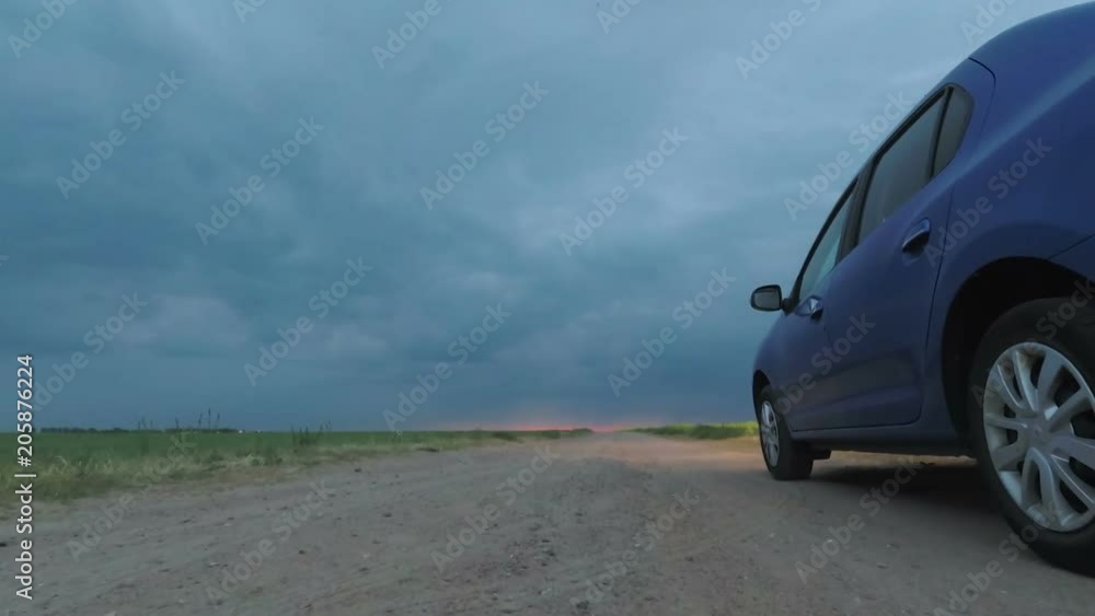 GOMEL, BELARUS - May 15, 2018: blue car parked in the field against a stormy sky. GOMEL, BELARUS - May 15, 2018: blue car parked in the field against a stormy sky.