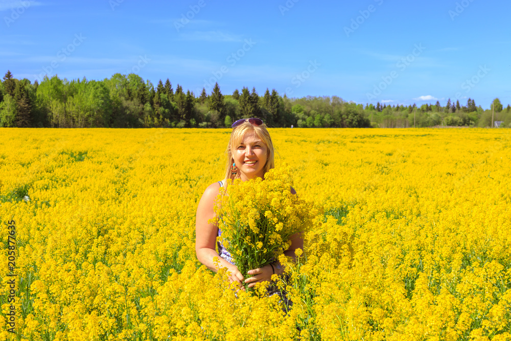 Fototapeta premium Happy blonde enjoys nature in a yellow field.