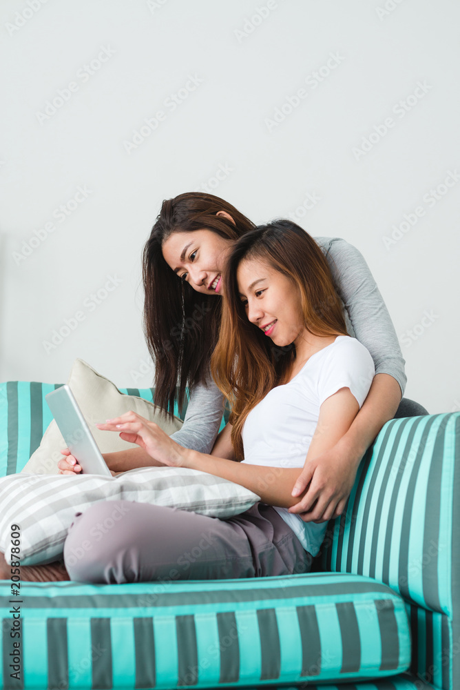 Beautiful young asian women LGBT lesbian happy couple sitting on sofa buying online using tablet in living room at home. LGBT lesbian couple together indoors concept. Spending nice time at home. Beautiful young asian women LGBT lesbian happy couple sitting on sofa buying online using tablet in living room at home. LGBT lesbian couple together indoors concept. Spending nice time at home.