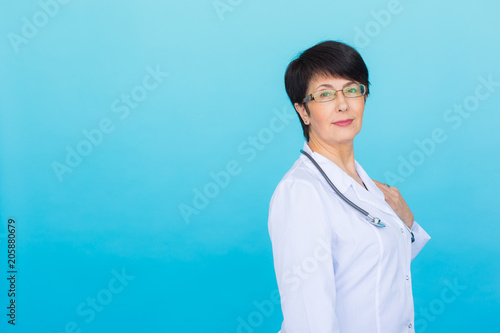 Smiling medical doctor woman with stethoscope. Over blue background with copy space