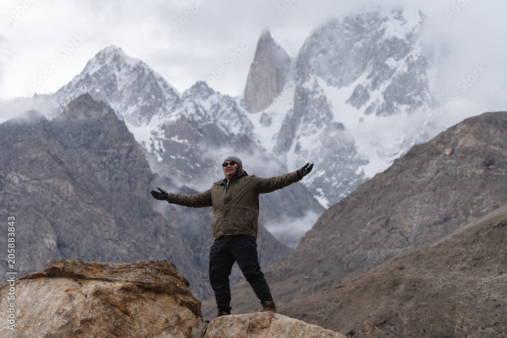 a man raising hand up on the mountain peak and Ladyfinger mountain peak background, in Pakistan