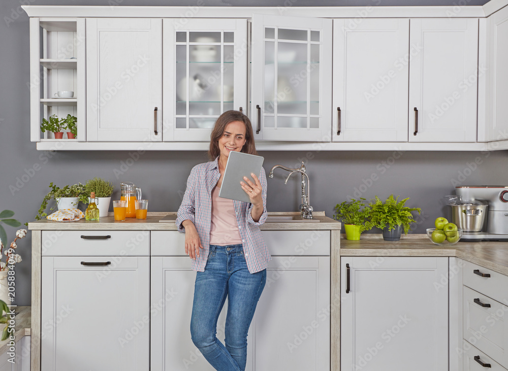 Young woman in kitchen with digital tablet Young woman in kitchen with digital tablet