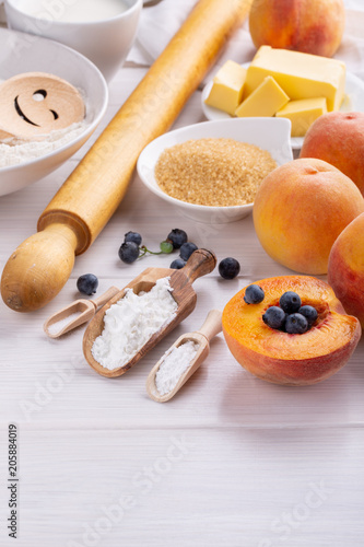 Ingredients for baking fruit pie on white table.