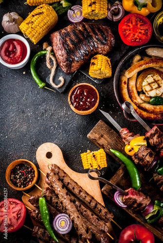Assortment various barbecue food grill meat  bbq party fest - shish kebab  sausages  grilled meat fillet  fresh vegetables  sauces  spices  dark rusty concrete table  above copy space