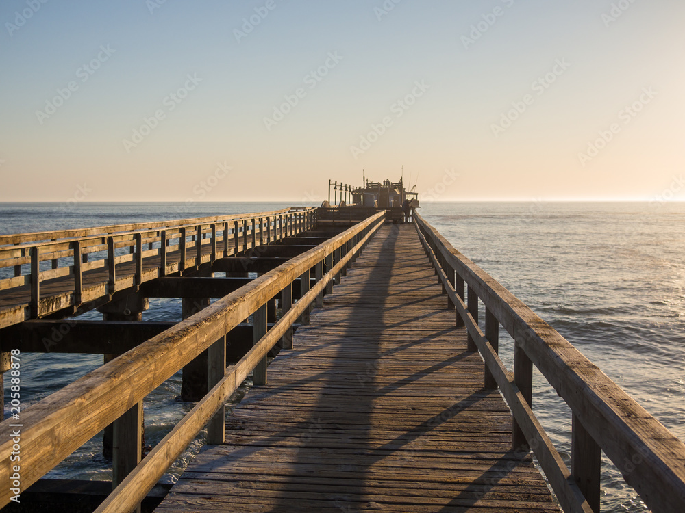 Φωτογραφία Wooden pier leading out into ocean with calm sea during soft sunset, Swakopmund,