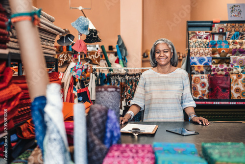 Smiling mature woman working in her colorful fabric shop