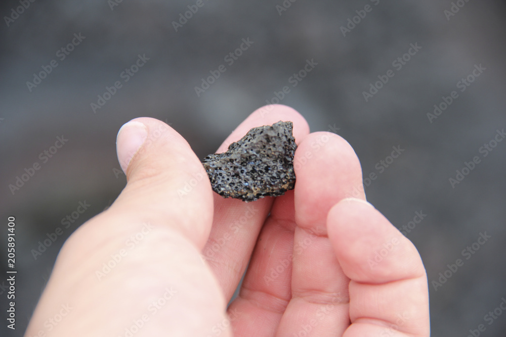 Close up of hand holding iridescent lava rock Close up of hand holding iridescent lava rock