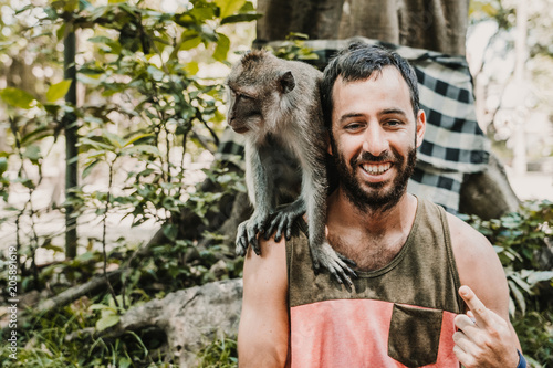 .Young handsome man taking himself some pictures with a cute monckey in the monckey forest in Ubud, Bali. Lifestyle. Travel photography photo