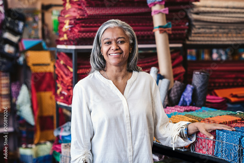 Smiling mature woman standing by cloth in her fabric store © mavoimages