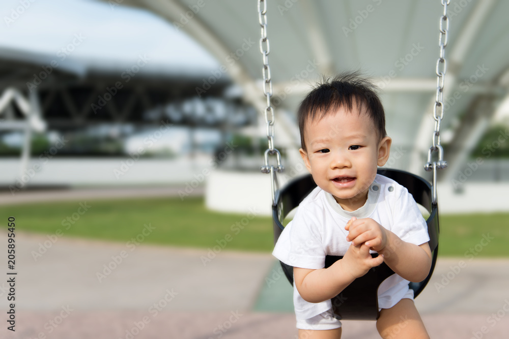 Adorable little Asian baby boy in swing at outdoor playground Adorable little Asian baby boy in swing at outdoor playground
