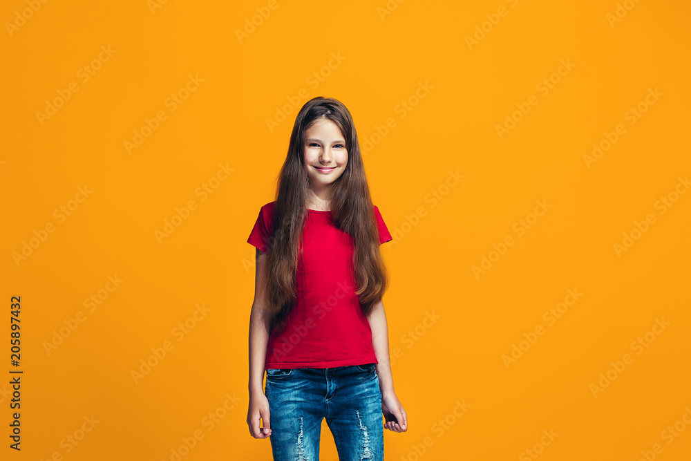 The happy teen girl pointing to you, half length closeup portrait on orange background. The happy teen girl pointing to you, half length closeup portrait on orange background.