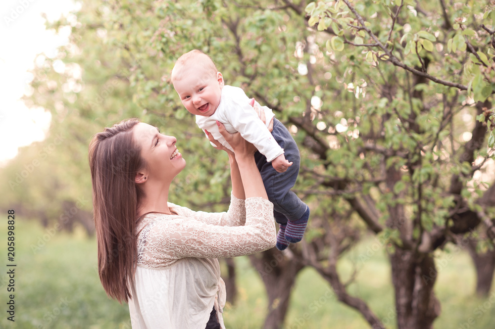 Fototapeta premium Smiling woman holding baby outdoors. Happiness. Motherhood.
