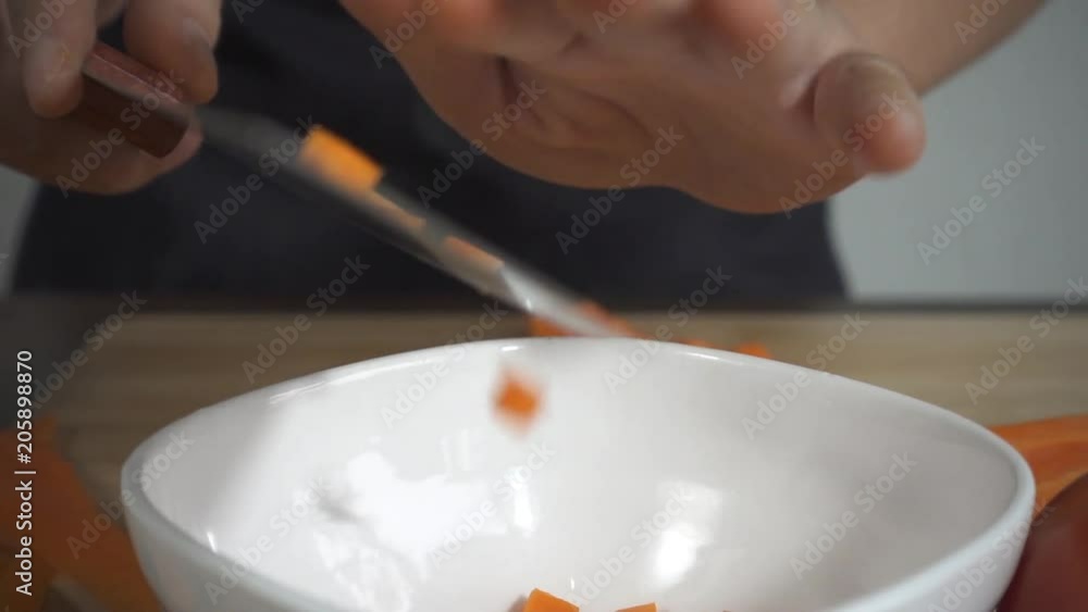 Slow motion - Close up of woman making healthy food and chopping carrot on cutting board in the kitchen. Slow motion - Close up of woman making healthy food and chopping carrot on cutting board in the kitchen.