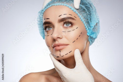 Woman in blue cap with puncture lines on face