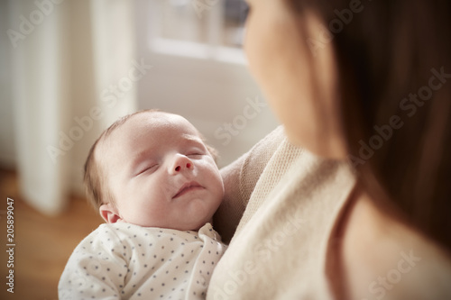Close Up Of Sleeping Newborn Baby Being Held By Mother