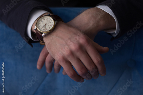 Close up of man hands wearing luxury watch. Business power concept.