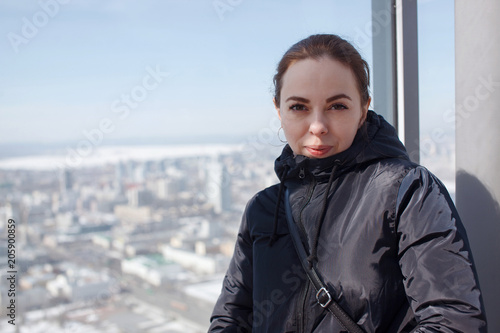 Woman standing near window in city and wearing leather jacket. Concept of walking outside and youth. photo
