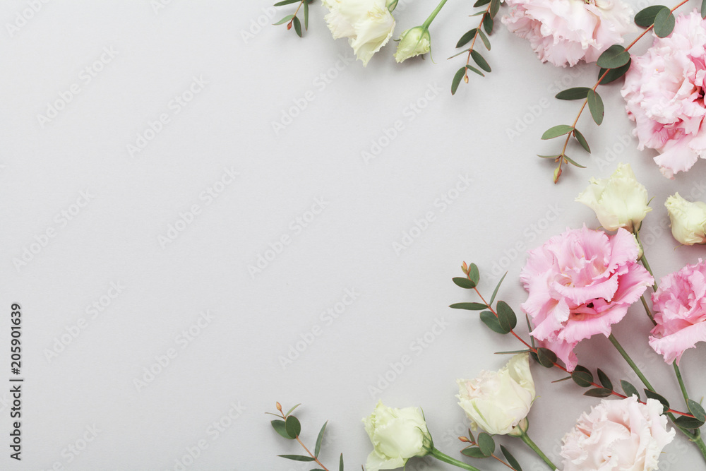 Floral border of beautiful flowers and green eucalyptus leaves on gray table top view. Flat lay composition.
