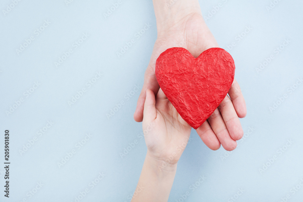 Doctor and kid holding red heart in hands. Family relationships, health care, pediatric cardiology concept.