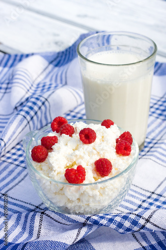 Milk and glass bowl with soft cheese and raspberry in summer