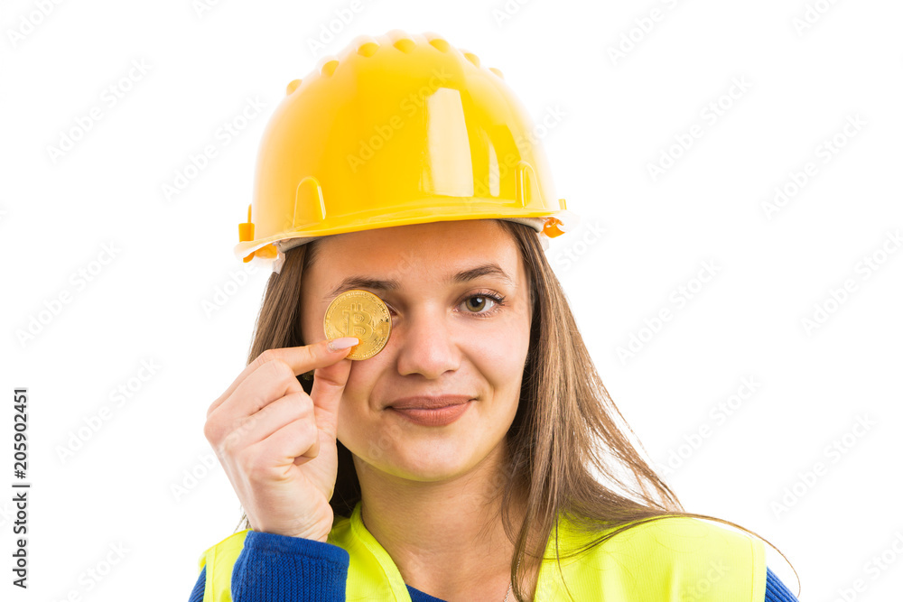 Young woman architect covering eye with bitcoin. Young woman architect covering eye with bitcoin.