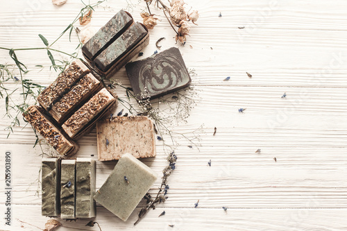 natural soap. handmade herbal soap with wildflowers, healing flowers, mint,  lavender, space text. eco natural product for skin care. soap on white rustic background with dried herbs, flat lay.