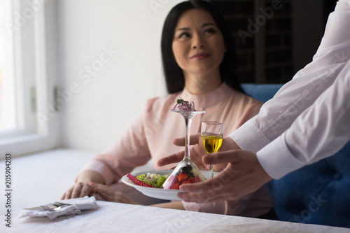 Businesswoman having lunch in luxury restaurant. Waiter serves her order.