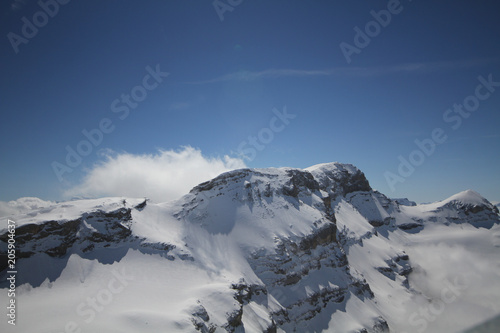 Majestical scene with ice mountains with snowy peaks middle of clouds, Landscape with beautiful high rocks and dramatic cloudy sky in clear blue bright day © biggereye