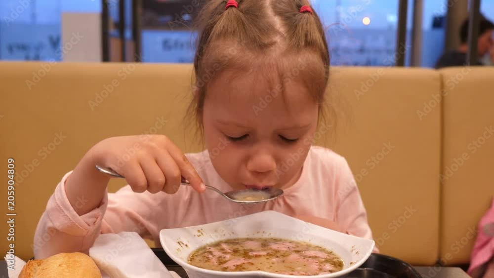 Petrol station food court child girl daughter portrait eating a soup with a spoon Petrol station food court child girl daughter portrait eating a soup with a spoon