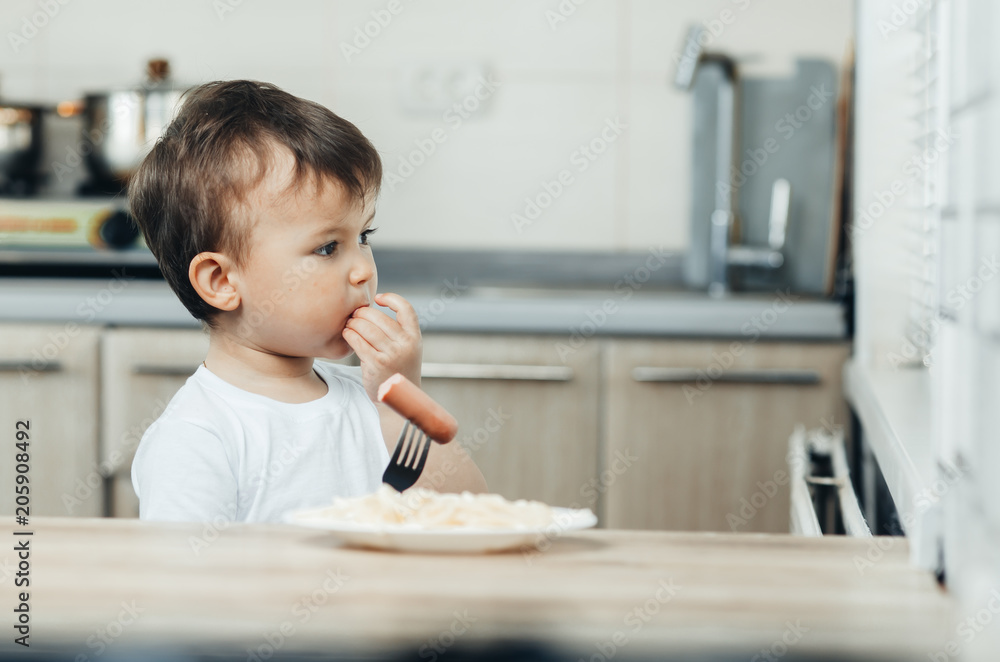 beautiful baby eating sausage with fork and smiling beautiful baby eating sausage with fork and smiling