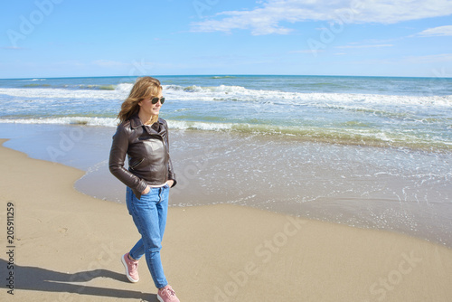 Woman standing at the beach in casual jeans and leather jacket © sepy