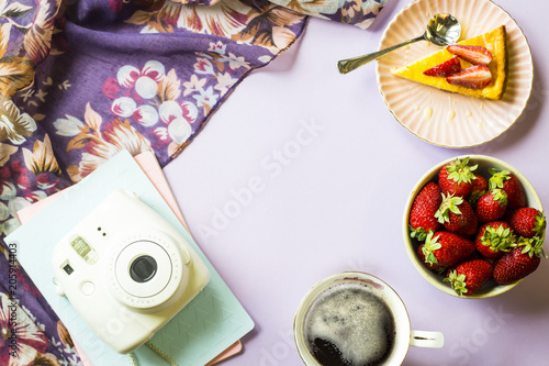 Spring breakfast with cheesecake  coffee and strawberries next to notepads and a scarf with floral print on a purple background. Copy space. Top view  flat lay