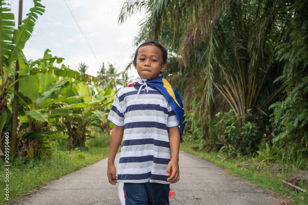 Joyful young boy with Malaysia flag in nature background. Merdeka theme ...