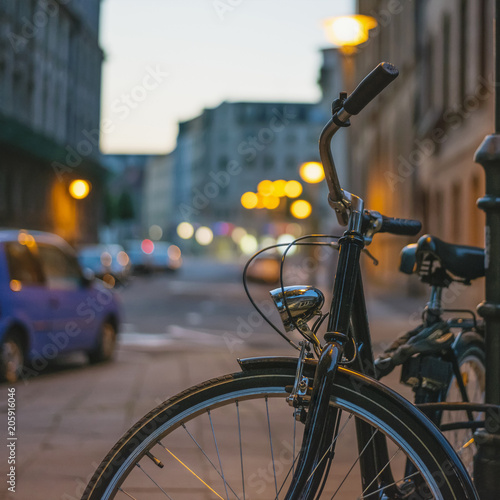 Bicycle in retro style fastened to a post in the dark on a street in a European city.