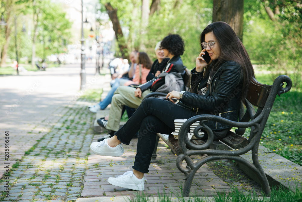 young pretty woman sitting in city park on bench. coffee to go. copy space young pretty woman sitting in city park on bench. coffee to go. copy space