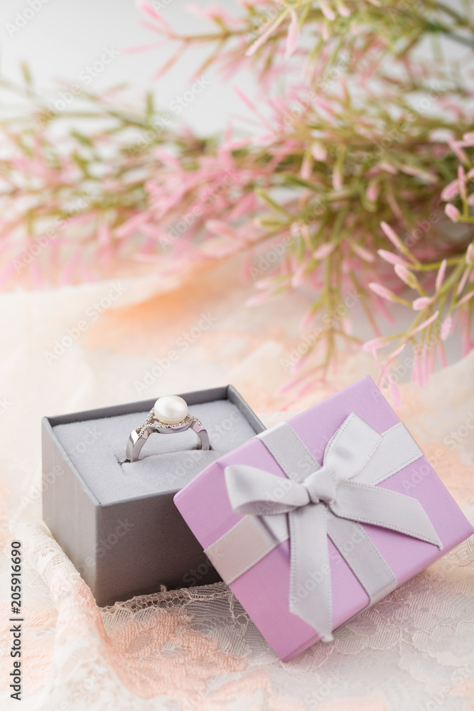 Pearl ring in pink gift box with bow on lace background Pearl ring in pink gift box with bow on lace background