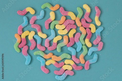 Colorful jelly sweets coated in sugar, against turquoise background, abstract