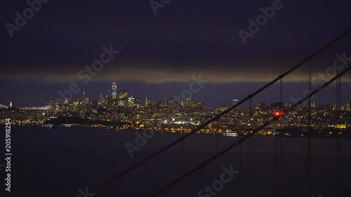 San Francisco lights through Golden Gate bridge cables at night - August 2017: San Francisco, California, US