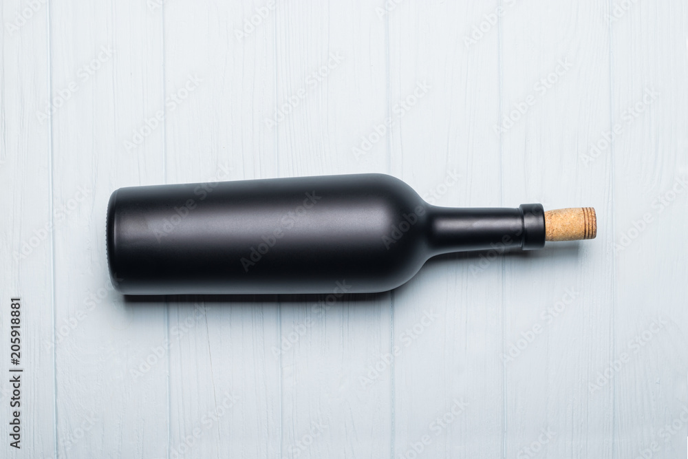 Fototapeta premium Wine bottle on white wooden background. Mock-up