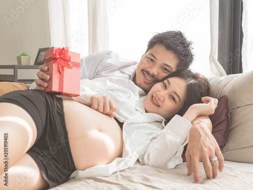 Portrait of a smiling husband giving gift box to his pregnant wife.pregnancy, parenthood and happiness concept - happy young family expecting child