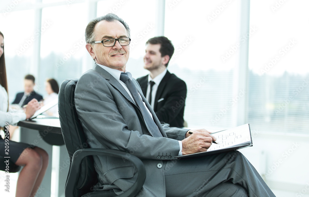 Fototapeta premium pensive mature businessman in suit with his team working behind