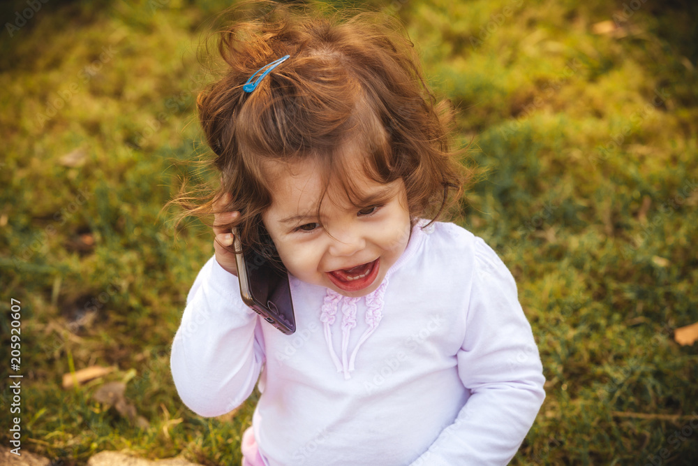 little girl with a mobile phone in the park little girl with a mobile phone in the park