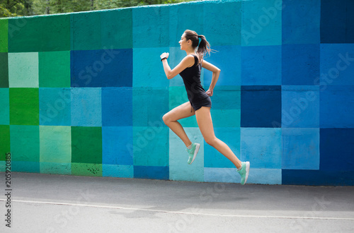 Side view of woman running against bright wall