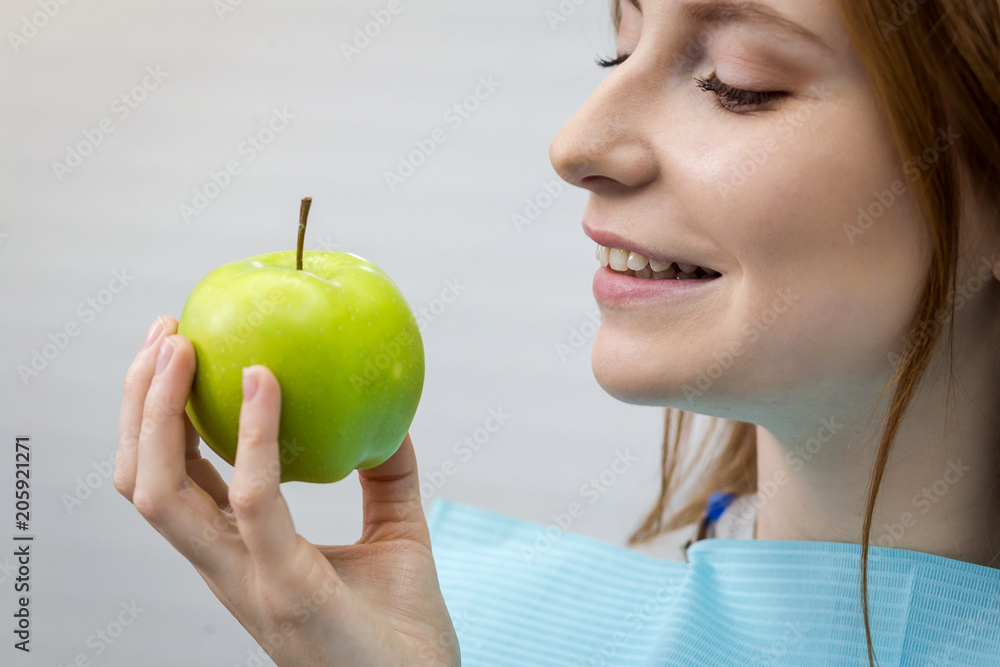 Young woman with healthy tooth biting green apple Young woman with healthy tooth biting green apple