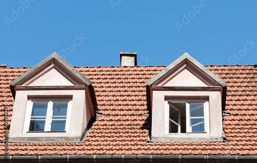 tiled roof with windows against the blue sky © ksena32