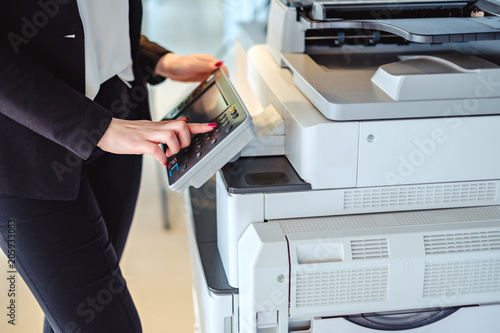 Woman pressing button on a copy machine in the office photo