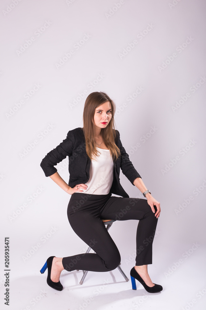 beautiful young business woman in black suit sits on a chair on white background beautiful young business woman in black suit sits on a chair on white background